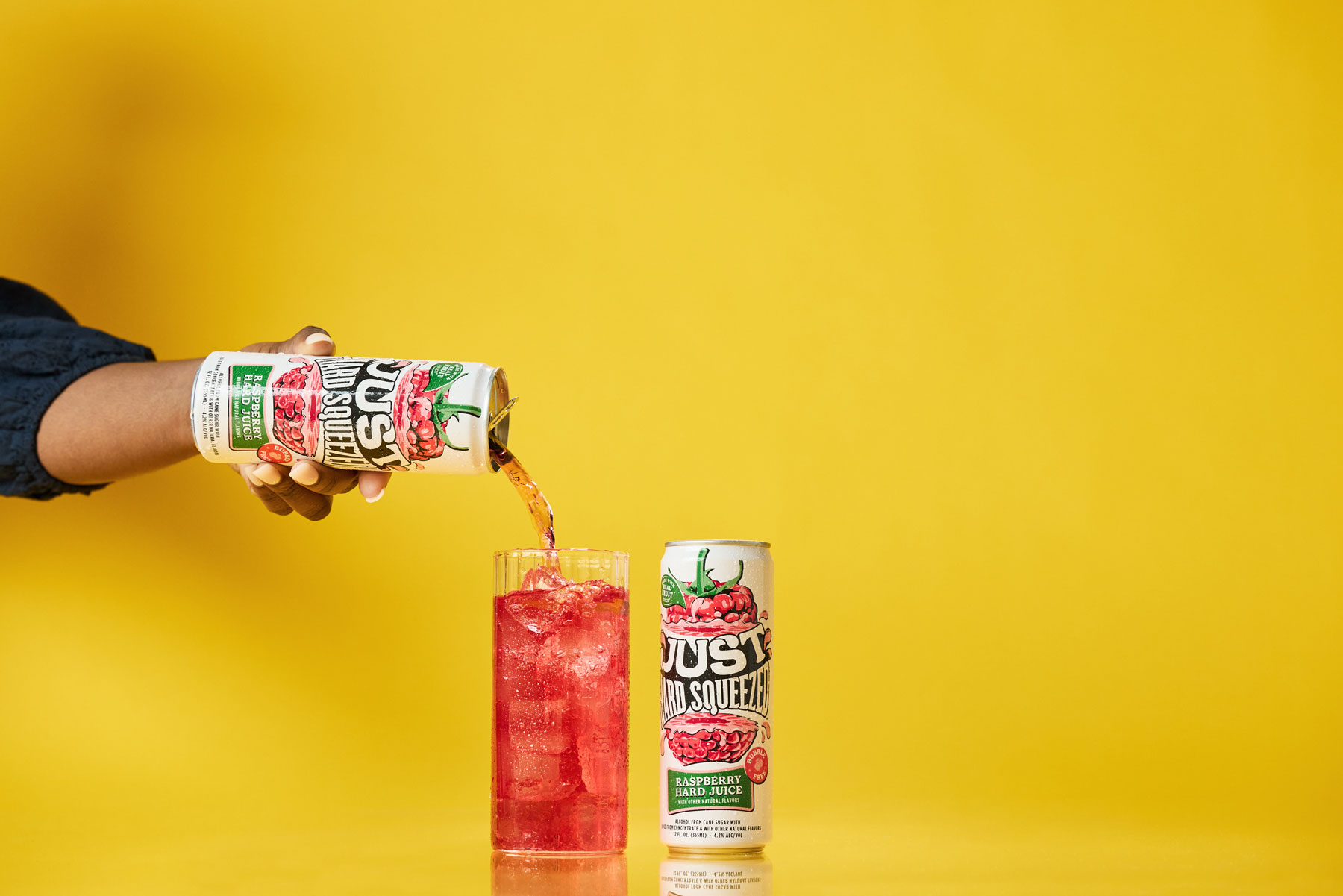 a can of just hard squeezed raspberry next to a glass being poured into