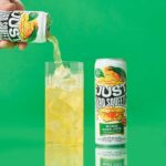 a can of just hard squeezed mango next to a glass being poured into