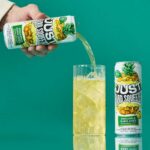 a can of just hard squeezed pineapple next to a glass being poured into