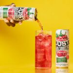 a can of just hard squeezed raspberry next to a glass being poured into