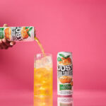a can of just hard squeezed peach next to a glass being poured into