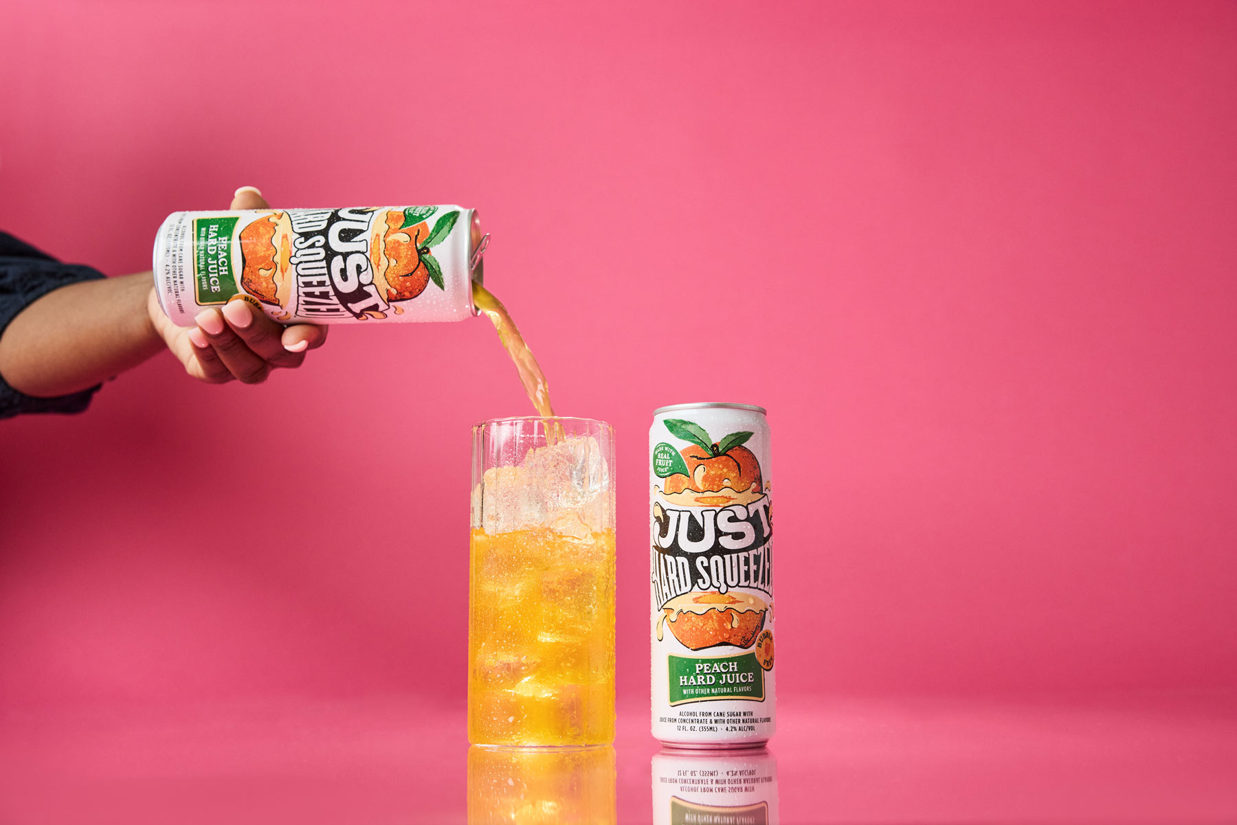 a can of just hard squeezed peach next to a glass being poured into