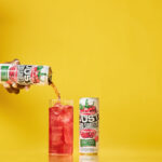 a can of just hard squeezed raspberry next to a glass being poured into