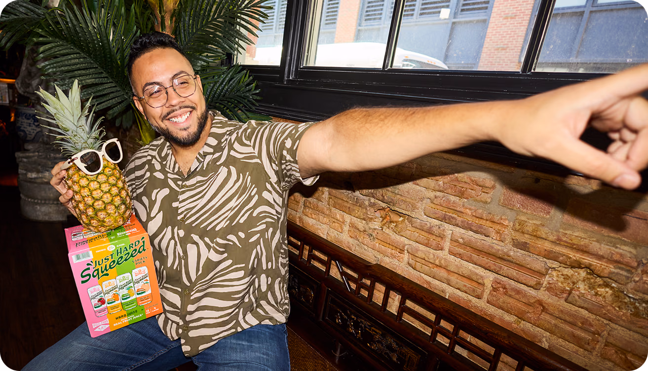 A man holding a package of Just Hard Squeezed and a pineapple