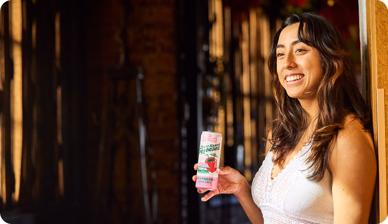 A woman holding a can of Just Hard Squeezed Raspberry